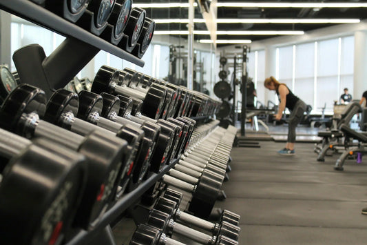 Set of black dumbbells placed on a gym floor, representing strength training and fitness equipment.